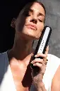 woman holding pomabrush black next to face.webp