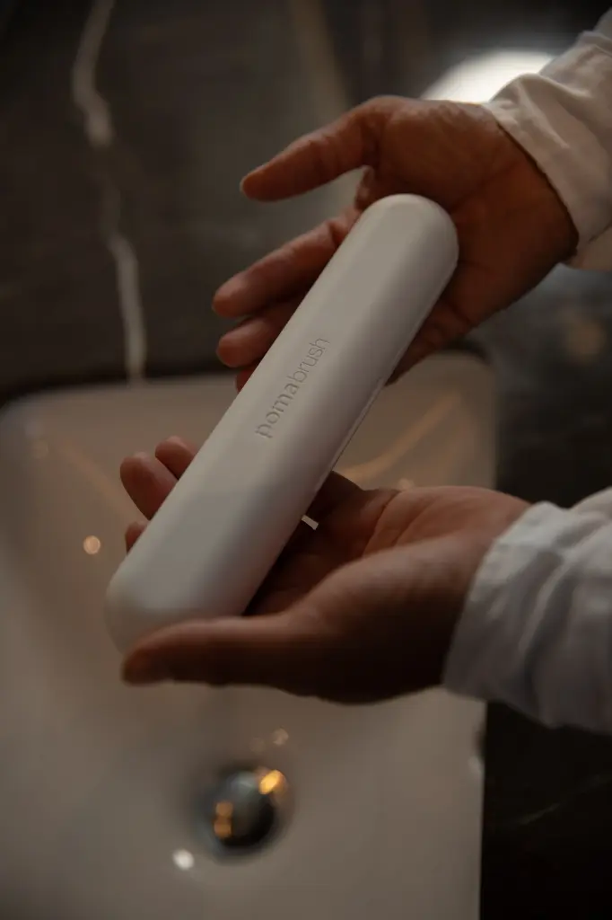 hands holding pomabrush white over basin.webp